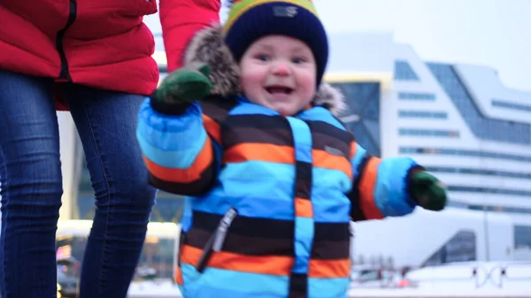 Mamma e bambino camminano per strada in inverno. Un bambino felice sta sorridendo alla telecamera. Rallentatore — Foto Stock