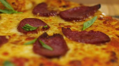 Ahşap bir masanın üzerinde taze taze, iştah açıcı peperoni pizza. Arka planda erkek ya da kadın şefin bulanık figürünün yeşillikleriyle dekore edilmiş. Ön manzara 4K video.