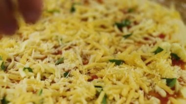 Bir erkek ya da kadın lezzetli bir pizza hazırlamakla meşgul. Pizza pişiriyorum. Şef, pizzanın dibine domates ezmesiyle yağlanmış peynir ve fesleğen koydu..