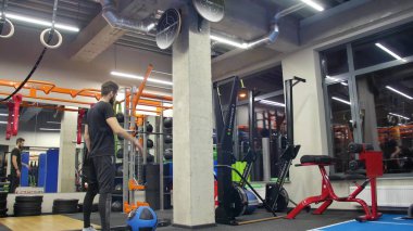 Spor kıyafetleri içinde spor salonunda spor salonunda ağır tıp topuyla egzersiz yapan güçlü genç bir adam. Çapraz antrenman yapan bir adam. - Evet. Kapat.