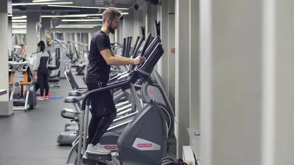 年轻的肌肉人在攀爬模拟器上锻炼.在一个健身房的背景下 — 图库照片