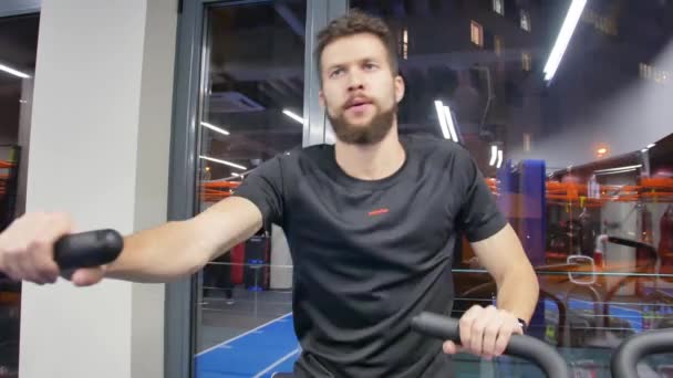 Молодой человек без рубашки делает упражнения на воздушном велосипеде в спортзале крупным планом — стоковое видео