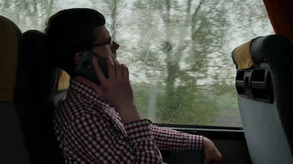 Young man checking emails on his commute to a job by the bus in a long trip. Close-up of using a mobile phone.