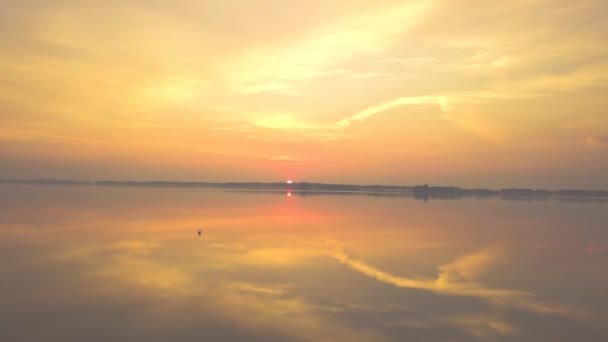 Increíblemente hermoso amanecer rojo-naranja en el lago. Reflejo de los rayos solares del sol naciente en la superficie del espejo del agua. Video aéreo, punto de vista del dron — Vídeos de Stock