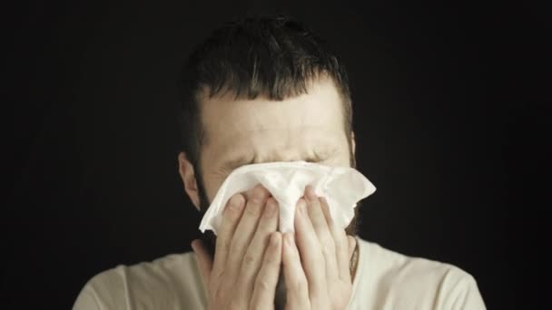 Młody człowiek z brodą i wąsami wbija nos w chusteczkę, zaskoczony tym, co widzi na chusteczce. Reakcja alergiczna, gorączka, objawy choroby układu oddechowego — Wideo stockowe