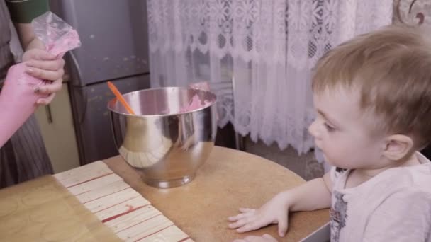 Um menino bonito parece que a mãe prepara marshmallows caseiros. Mãe ensina bebê a cozinhar doces caseiros — Vídeo de Stock