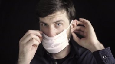 Adam maske takıyor. Yüz maskesi takmanın kuralları. Alerjik reaksiyonlara karşı solunum koruması. Bir erkeğin yüzüne yakın çekim. Burun ve gözleri COVID-19 koronavirüsünden koruyorum..