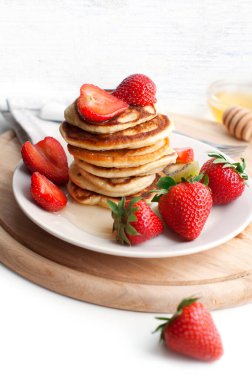 Beyaz arka planda krep, çilek, kivi ve bal ile kahvaltı. Tahtadaki çocuk için lezzetli bir kahvaltı.