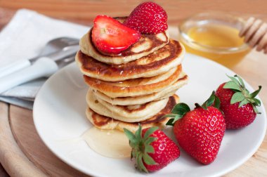 Beyaz arka planda krep, çilek, kivi ve bal ile kahvaltı. Tahtadaki çocuk için lezzetli bir kahvaltı.