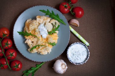Koyu kahverengi arka planda krema-sarımsak soslu fırında karnabahar ve domates. Üst görünüm