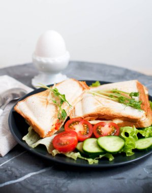 Krem peynirli, salatalıklı, jambonlu, domatesli ve bezelyeli sandviç. Beyaz stantta yumurta buğusuyla kahvaltı. 