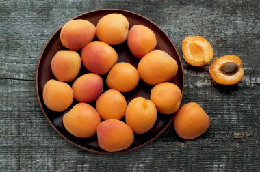 Tahta arka planda kahverengi tabakta olgun kayısılar. Üst görünüm