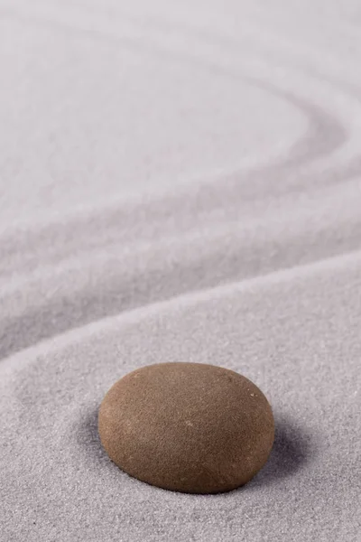 Zen meditation stone to focus and concentrate for a quit peace of mind. Spiritual raked sand background texture. Concept for harmony purity and spirituality.