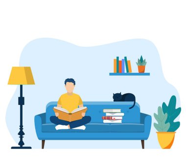 Genç adam evdeki sandalyede kitap okuyor.