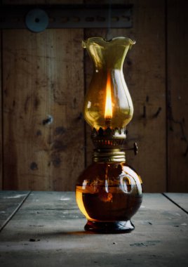 Ahşap masada yanan eski bir gaz lambası.