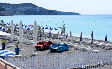 Deniz, sahil, şemsiyeler, plaj şezlongları ve Fransa 'nın Nice kentindeki Gezinti güvertesinde pedal botları.