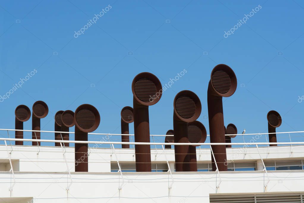 Rusty air duct pipes and roof on an garage against a blue sky