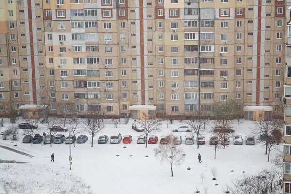 View from above to the yard of residential building after snowfall with snow covered cars. Selective focus