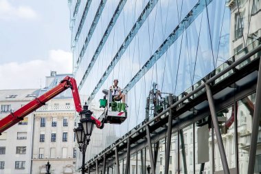 İşçi, binanın camını yıkıyor.