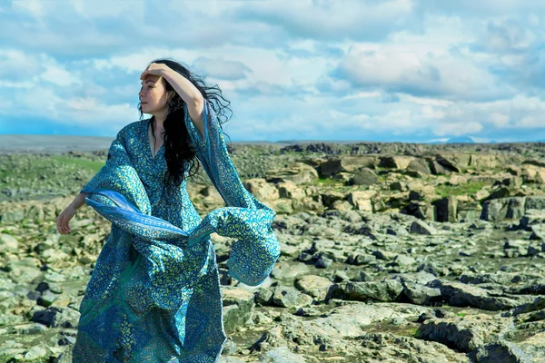 Femme en robe bleue sur champ de lave Image En Vente