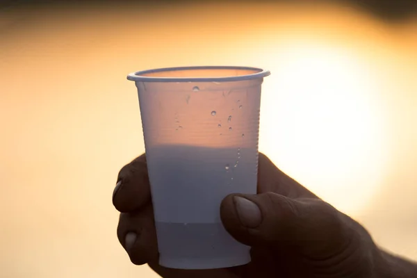 Glas in de hand bij zonsondergang — Stockfoto