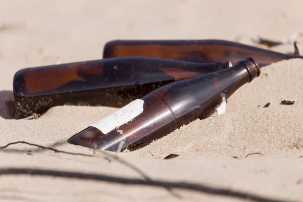 Glass bottles in the sand on nature. trash — Stock Photo, Image