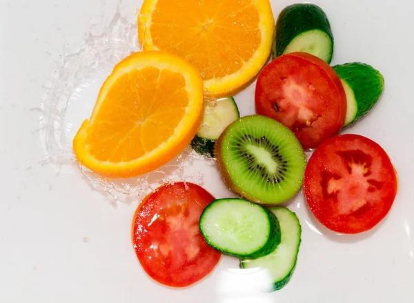Свежие фрукты и овощи в воде на белом фоне — стоковое фото