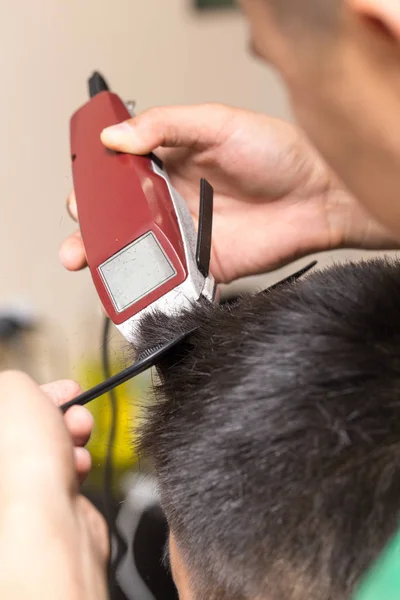 Hombre que tiene un corte de pelo con un cortador de pelo — Foto de Stock