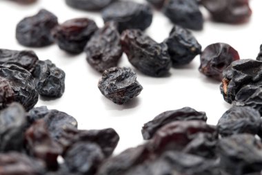 Beyaz arka planda siyah kuru üzüm. makro