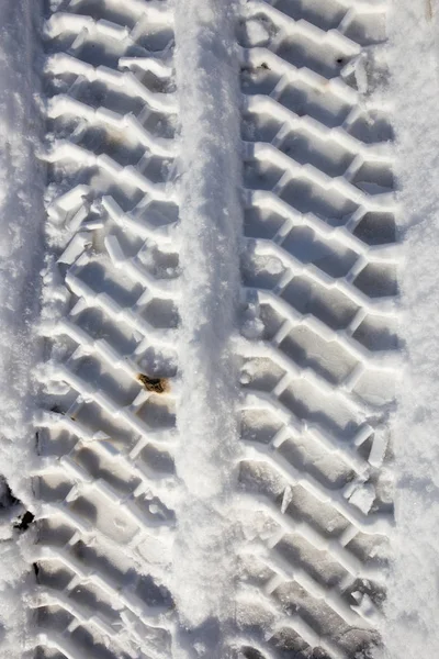 Spår av bilen i snön med asfalt — Stockfoto