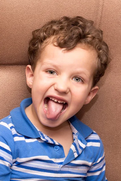 Curly haired boy showing tongue — Stock Photo, Image