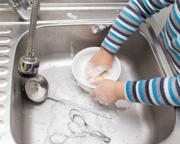 Мальчик моет посуду на кухне — стоковое фото