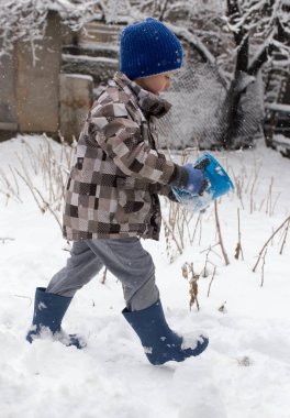 Çocuk kışın karla oynuyor.