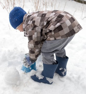 Çocuk kışın karla oynuyor.