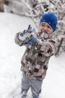Çocuk kışın karla oynuyor.