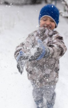 Çocuk kışın karla oynuyor.