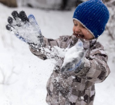 Çocuk kışın karla oynuyor.