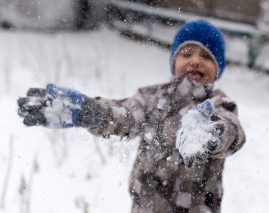 Çocuk kışın karla oynuyor.