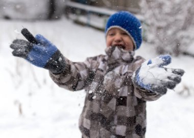 Çocuk kışın karla oynuyor.