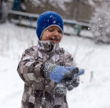 Çocuk kışın karla oynuyor.
