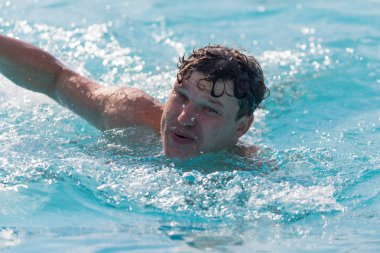 Adam havuzda yüzüyor.