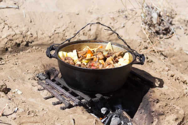 Carne com batatas em um caldeirão no fogo — Fotografia de Stock