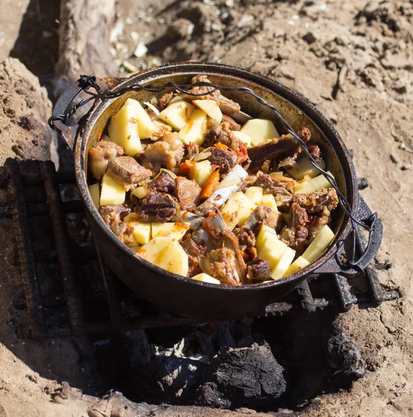 Vlees met aardappelen in een ketel in brand — Stockfoto