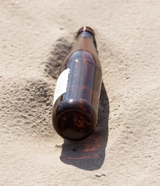 Glasflaskor i sanden på naturen. papperskorgen — Stockfoto