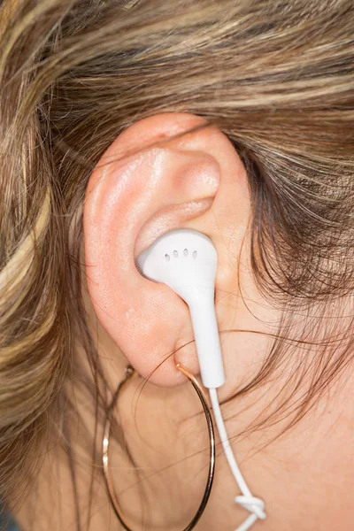 Fones de ouvido brancos em uma orelha de meninas — Fotografia de Stock