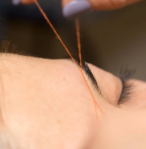 Grooming the eyebrows thread in a beauty salon. close — Stock Photo, Image