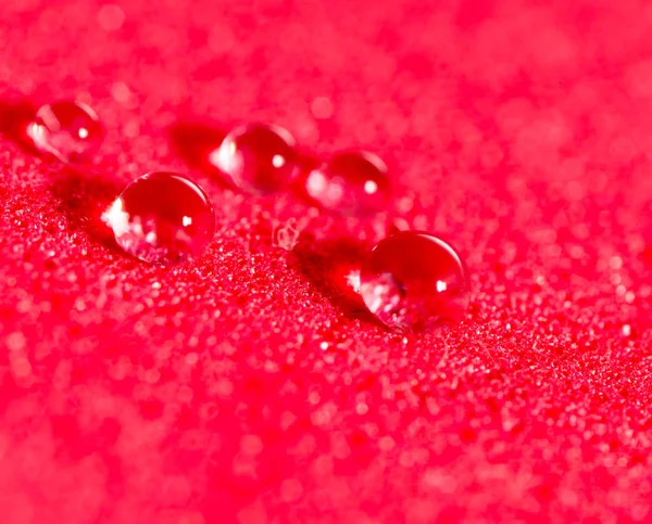 Крапля води на червоному тлі. закрити — стокове фото