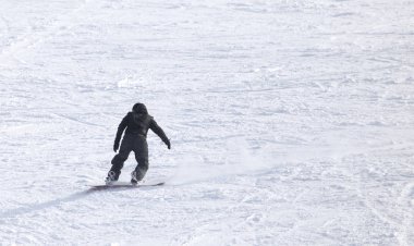 İnsanlar kışın karda snowboard yapıyor.