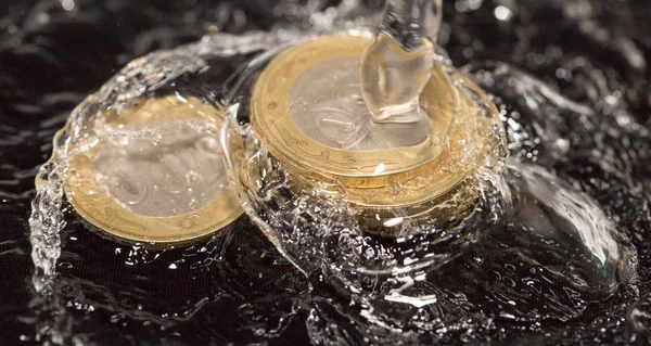 Monedas en salpicaduras de agua sobre un fondo negro — Foto de Stock