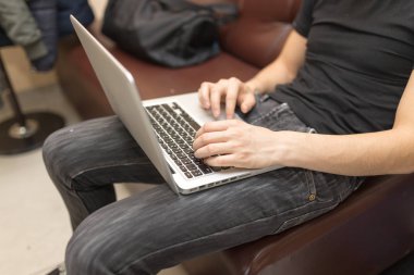 Dizüstü bilgisayarda çalışan genç bir adam.